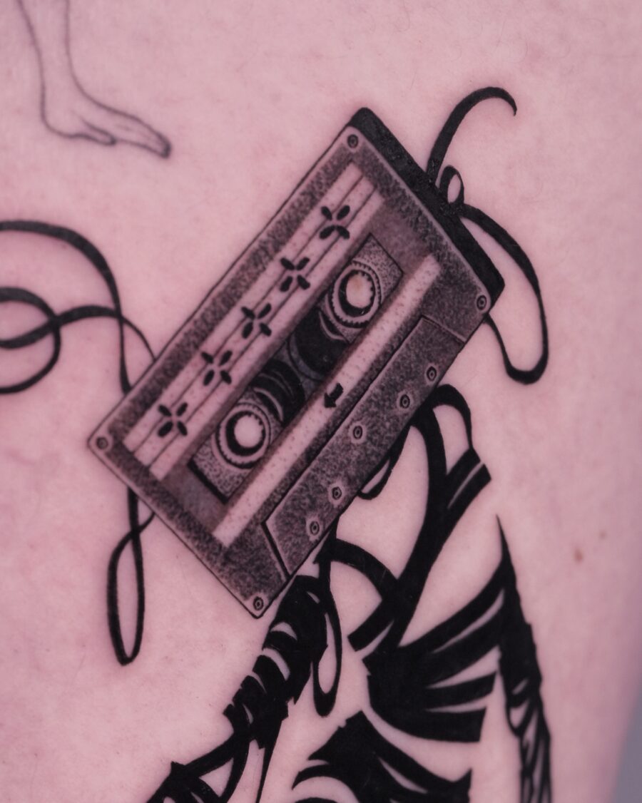 Realistic cassette tattoo with flowing tape details