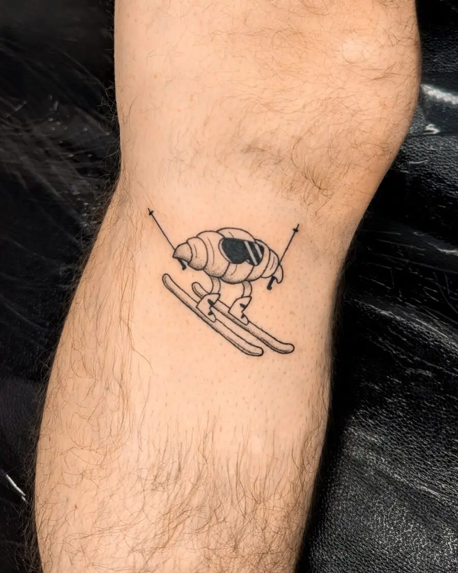 Whimsical skiing croissant tattoo design