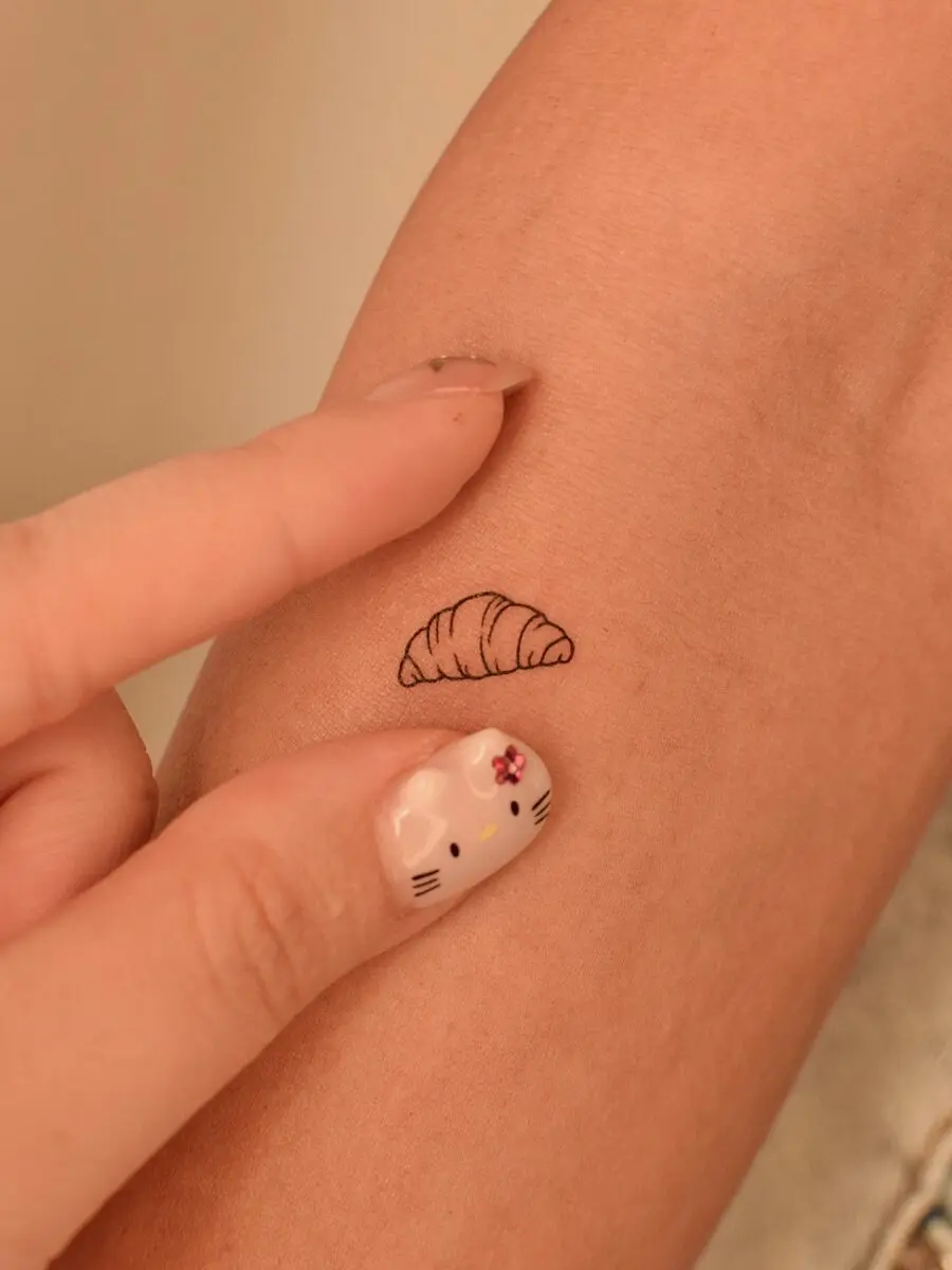 Charming minimalist croissant tattoo on skin