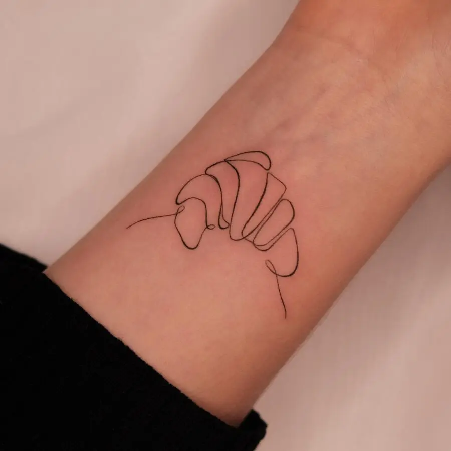 Elegant line art croissant tattoo design