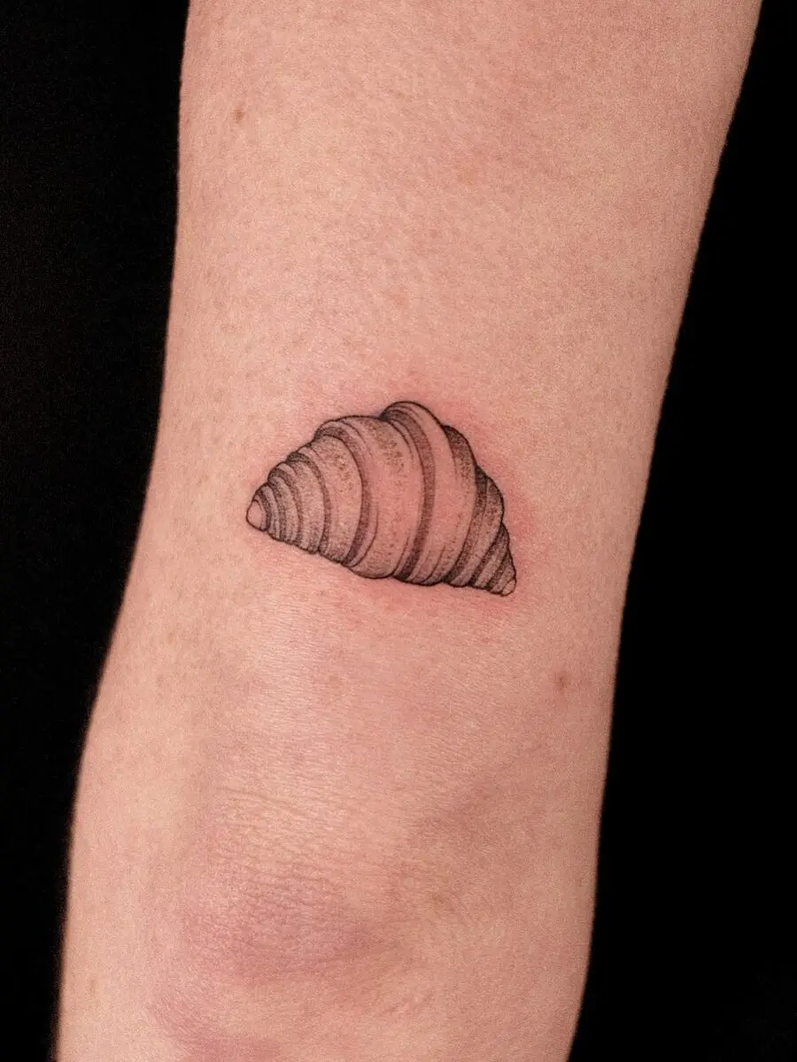 Charming croissant tattoo on the forearm