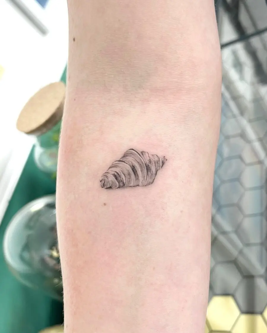 Realistic croissant tattoo on forearm