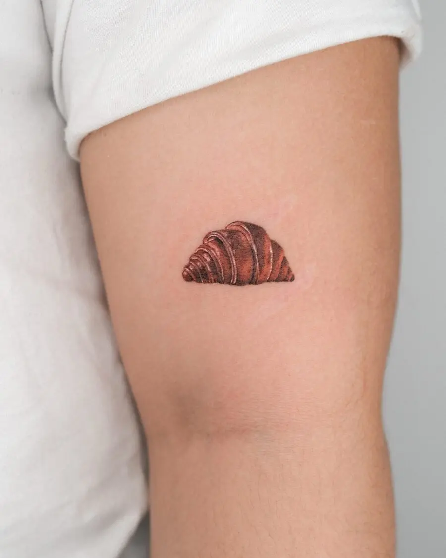 Realistic croissant tattoo on arm