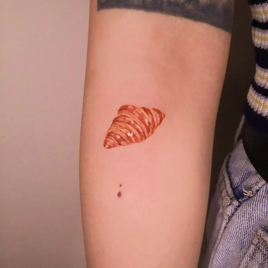 Charming croissant tattoo on a forearm