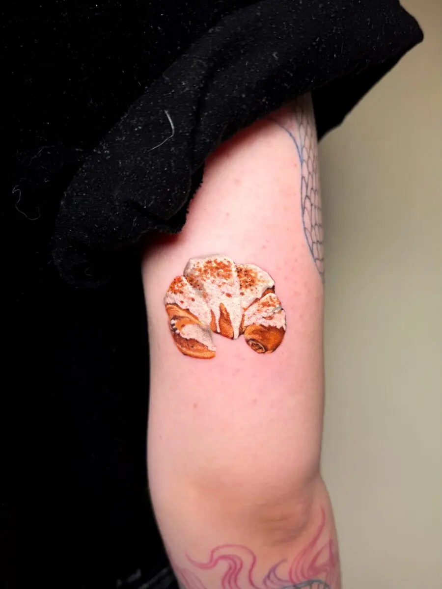 Charming croissant tattoo on an elegant arm