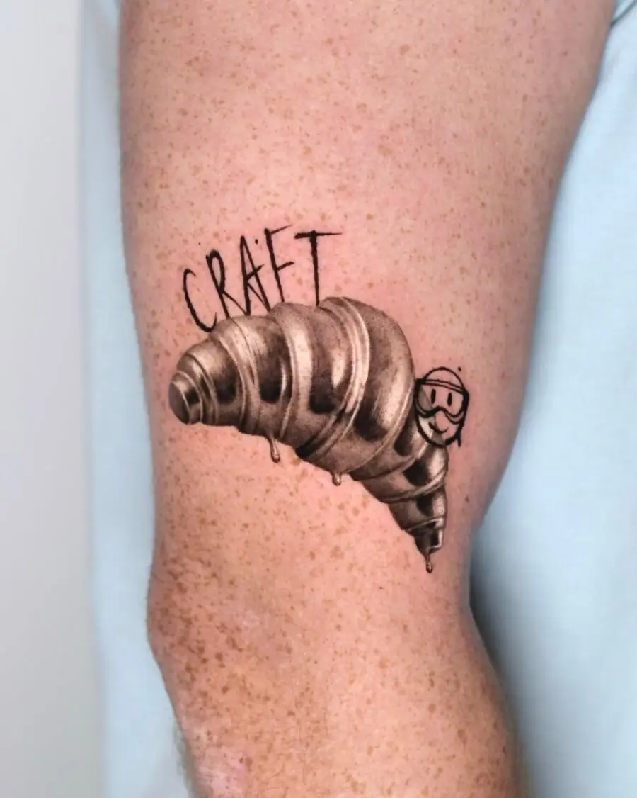 Playful Croissant Tattoo Featuring a Smiley Face