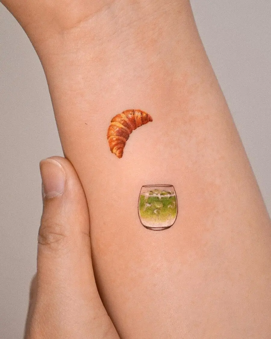 Charming croissant and vibrant drink tattoo.