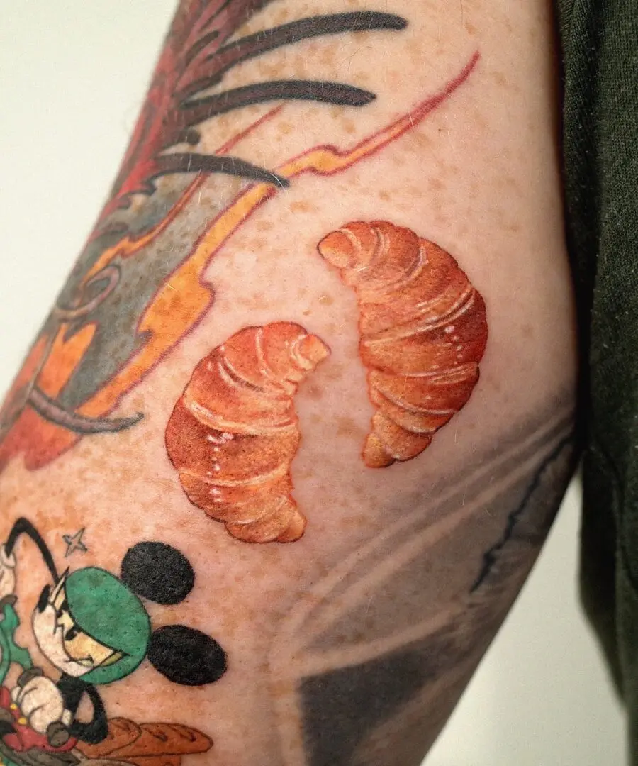Whimsical croissant tattoos with cartoon influence