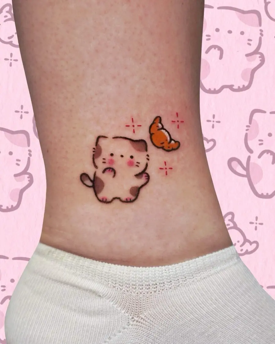 Adorable cat tattoo with a croissant charm