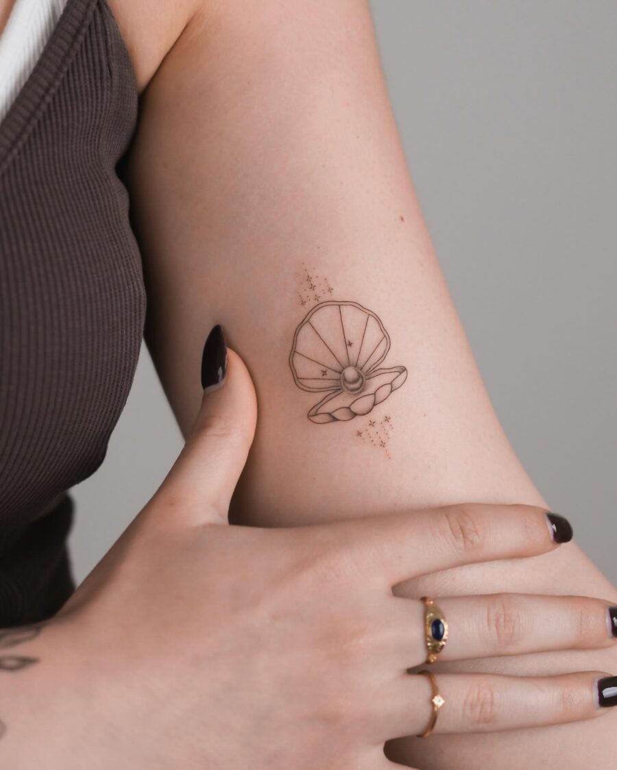 Elegant shell tattoo adorned with delicate stars