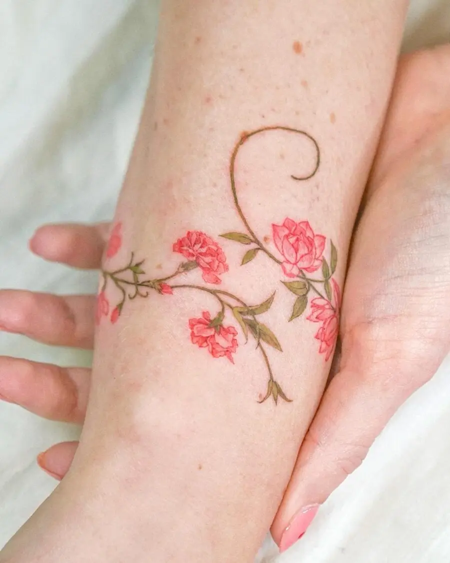 Delicate pink flower tattoo on arm