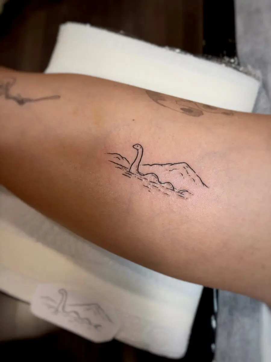 Charming minimalist Loch Ness Monster tattoo
