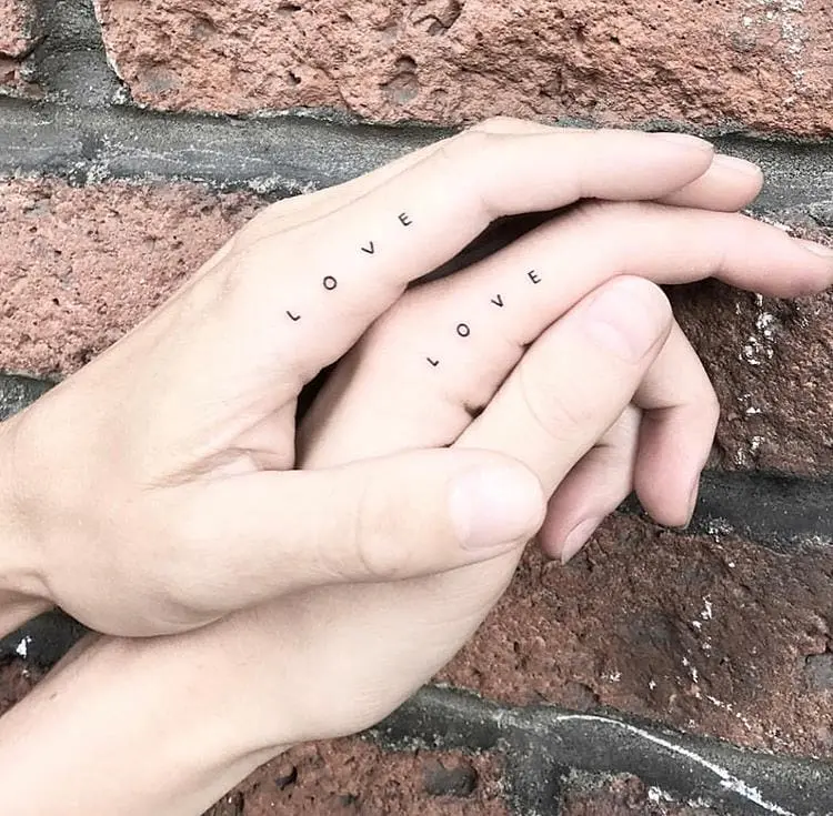 Minimalist LOVE tattoos on couple's hands
