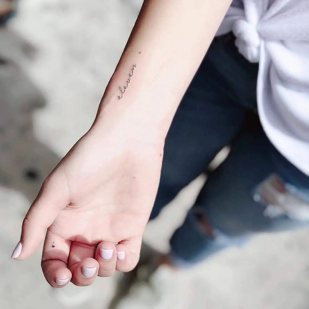 Minimalist tattoo featuring the word 'eleven'