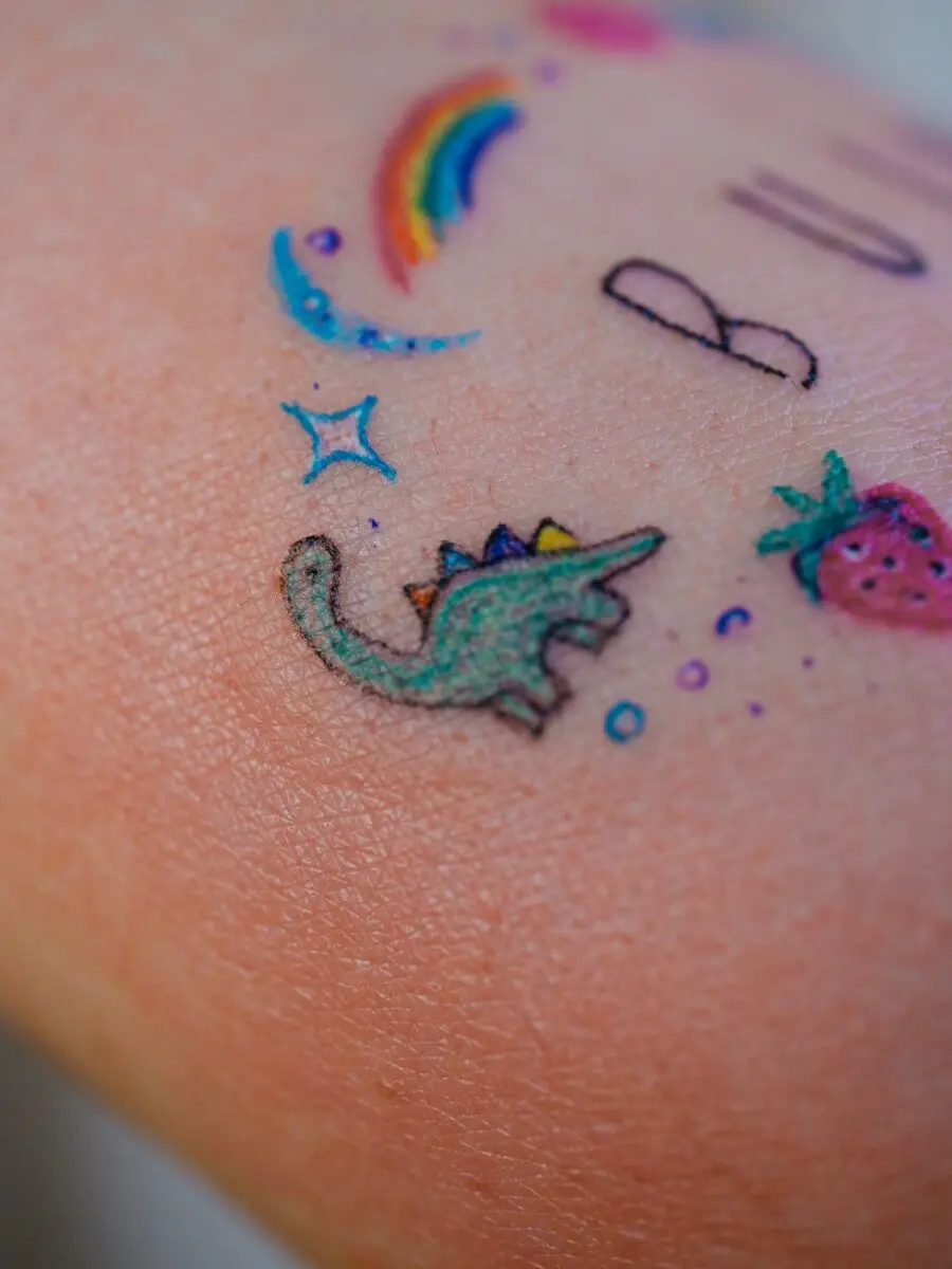 Whimsical rainbow baby dinosaur tattoo design