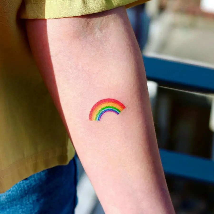 Vibrant small rainbow tattoo on forearm