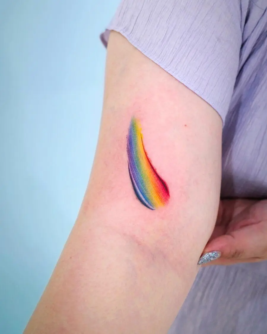 Vibrant rainbow baby tattoo on relaxed arm