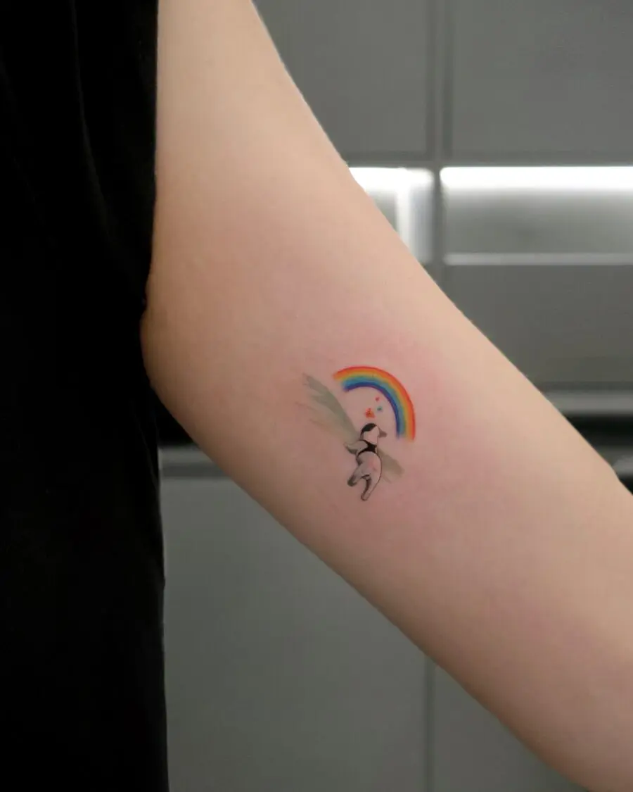 Whimsical unicorn under a vibrant rainbow tattoo