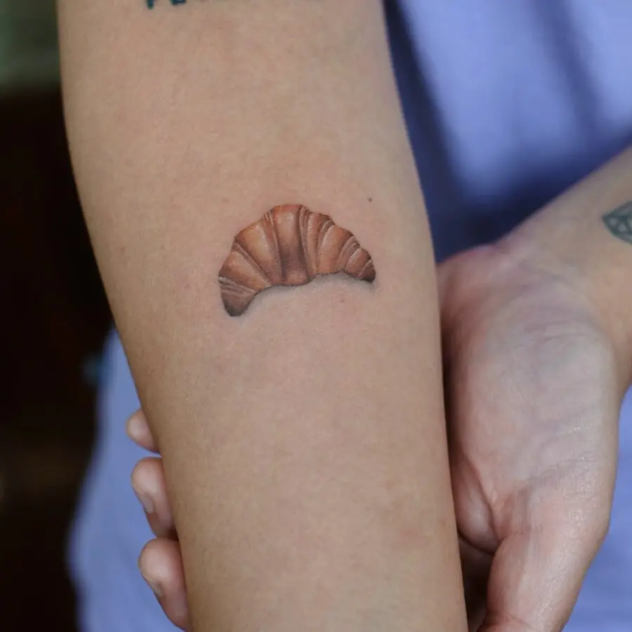Delightfully detailed croissant tattoo on forearm