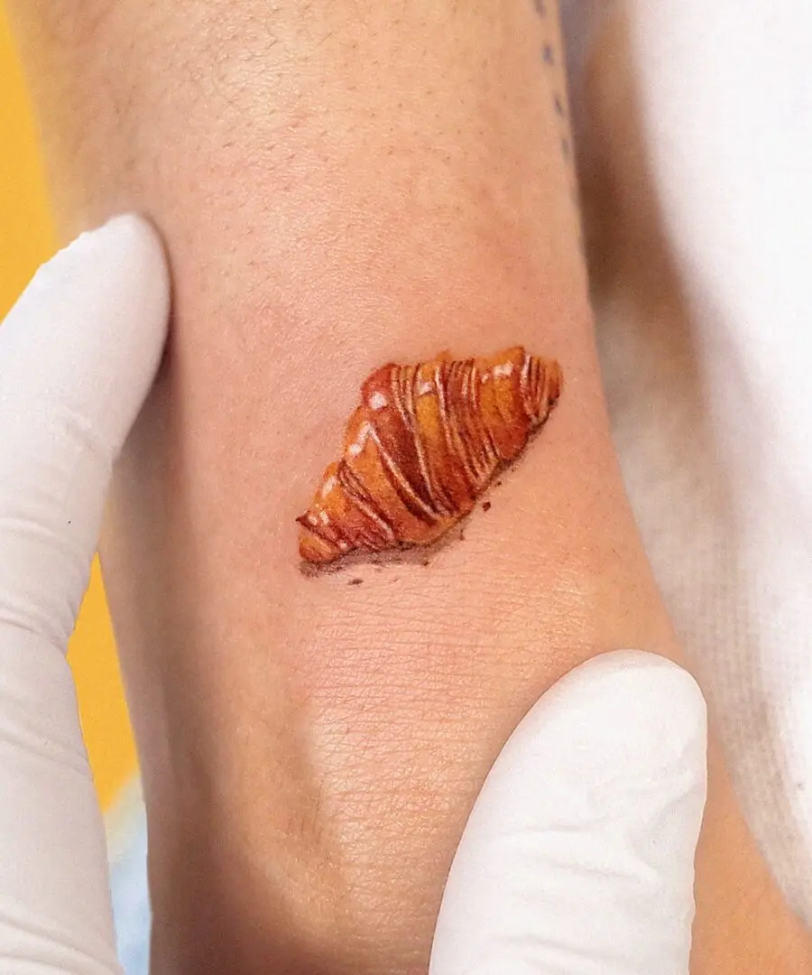 Deliciously detailed croissant tattoo on skin