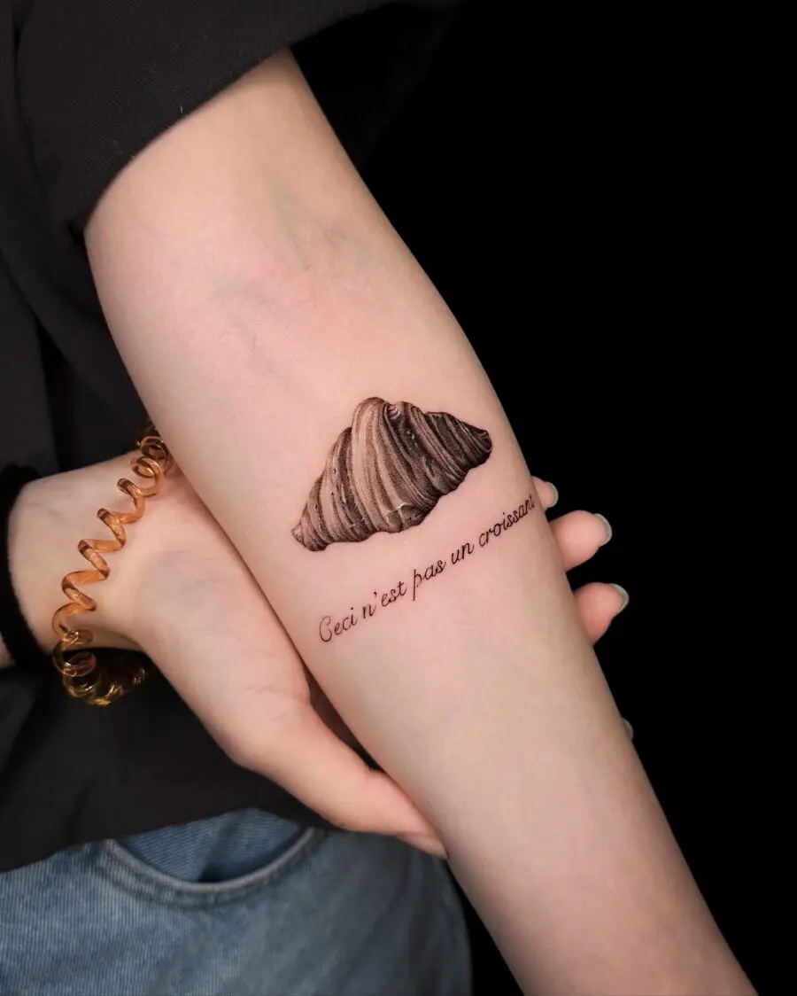 Whimsical croissant tattoo with clever text