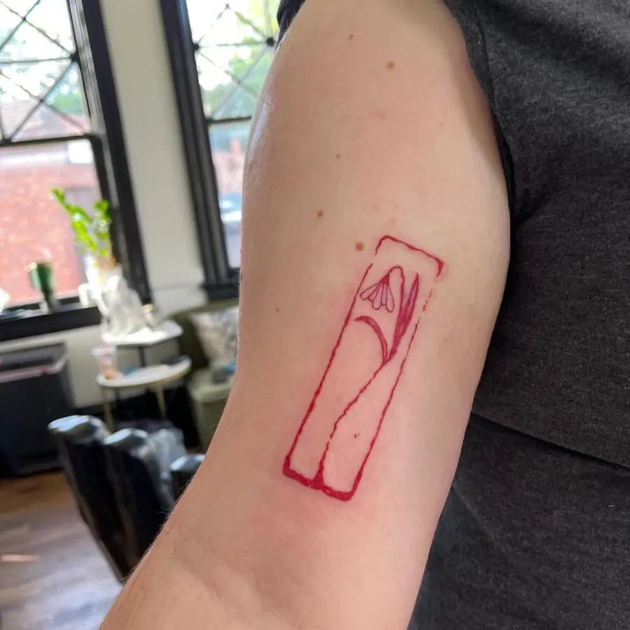 Minimalist snowdrop tattoo on arm.