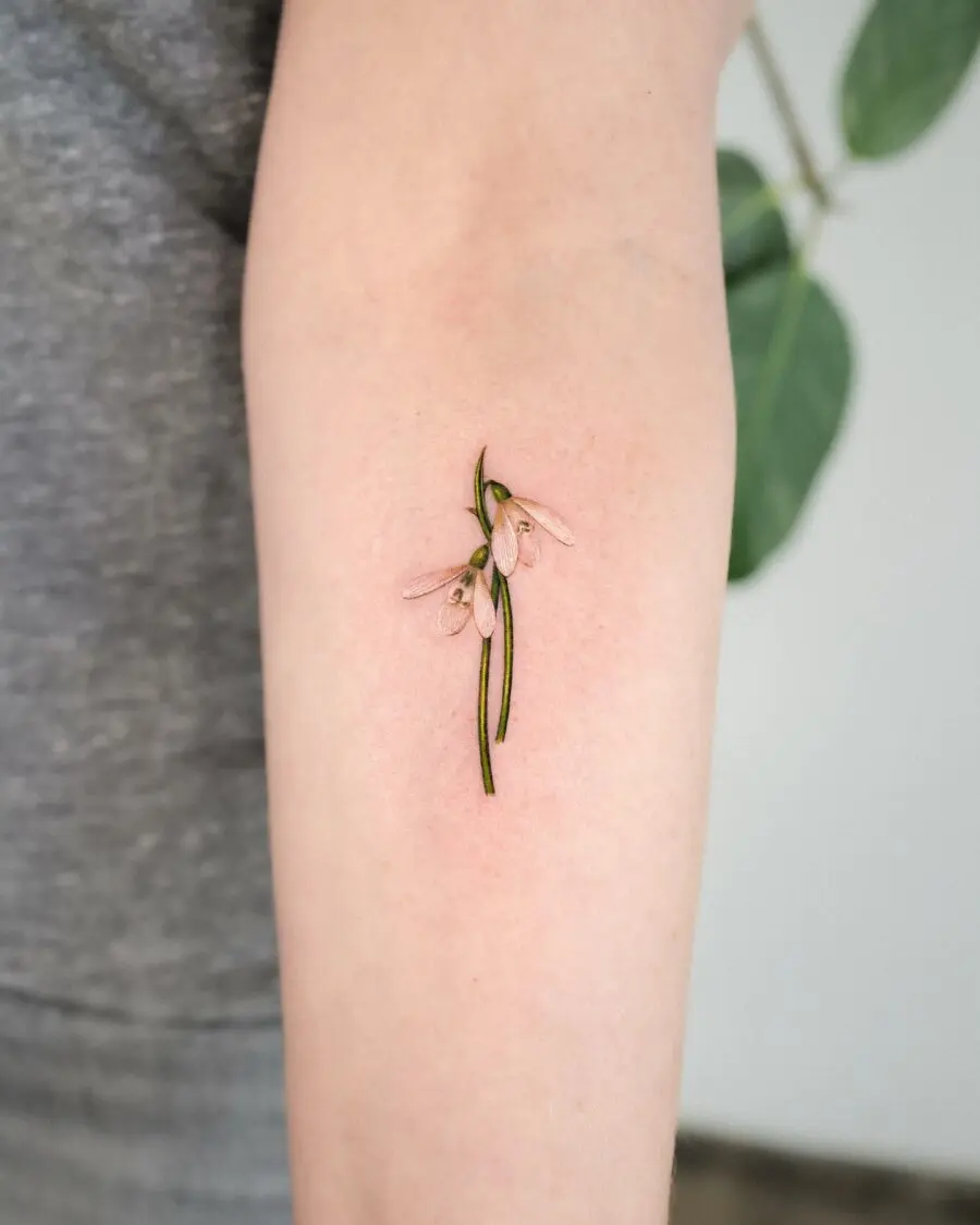 Delicate snowdrop tattoo on a forearm