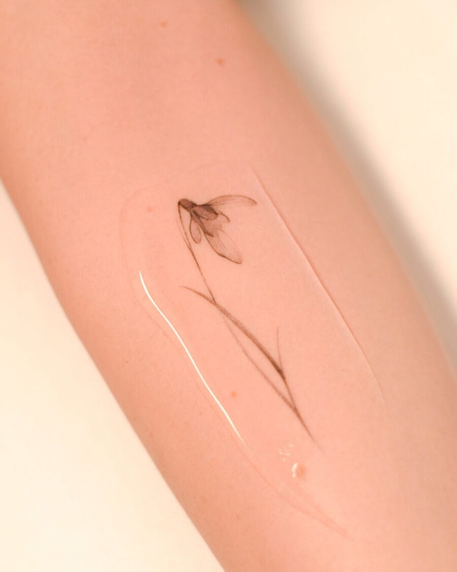 Delicate snowdrop flower tattoo on forearm