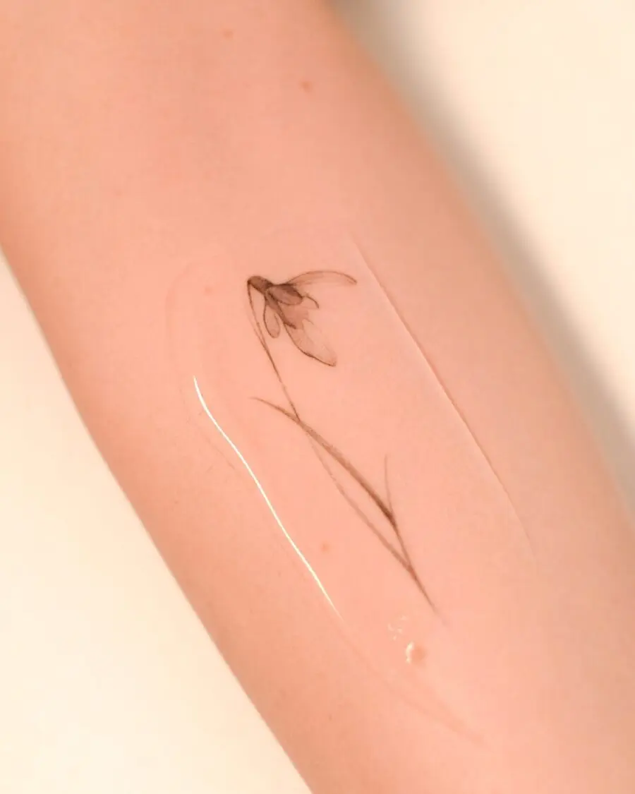 Delicate snowdrop flower tattoo on forearm