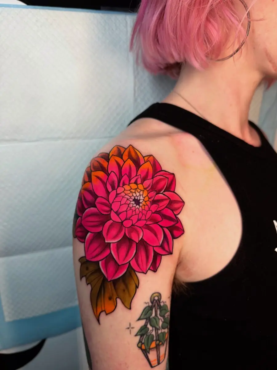 Vibrant pink dahlia tattoo on shoulder