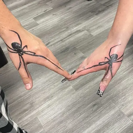 Intricate spider tattoos connecting two hands