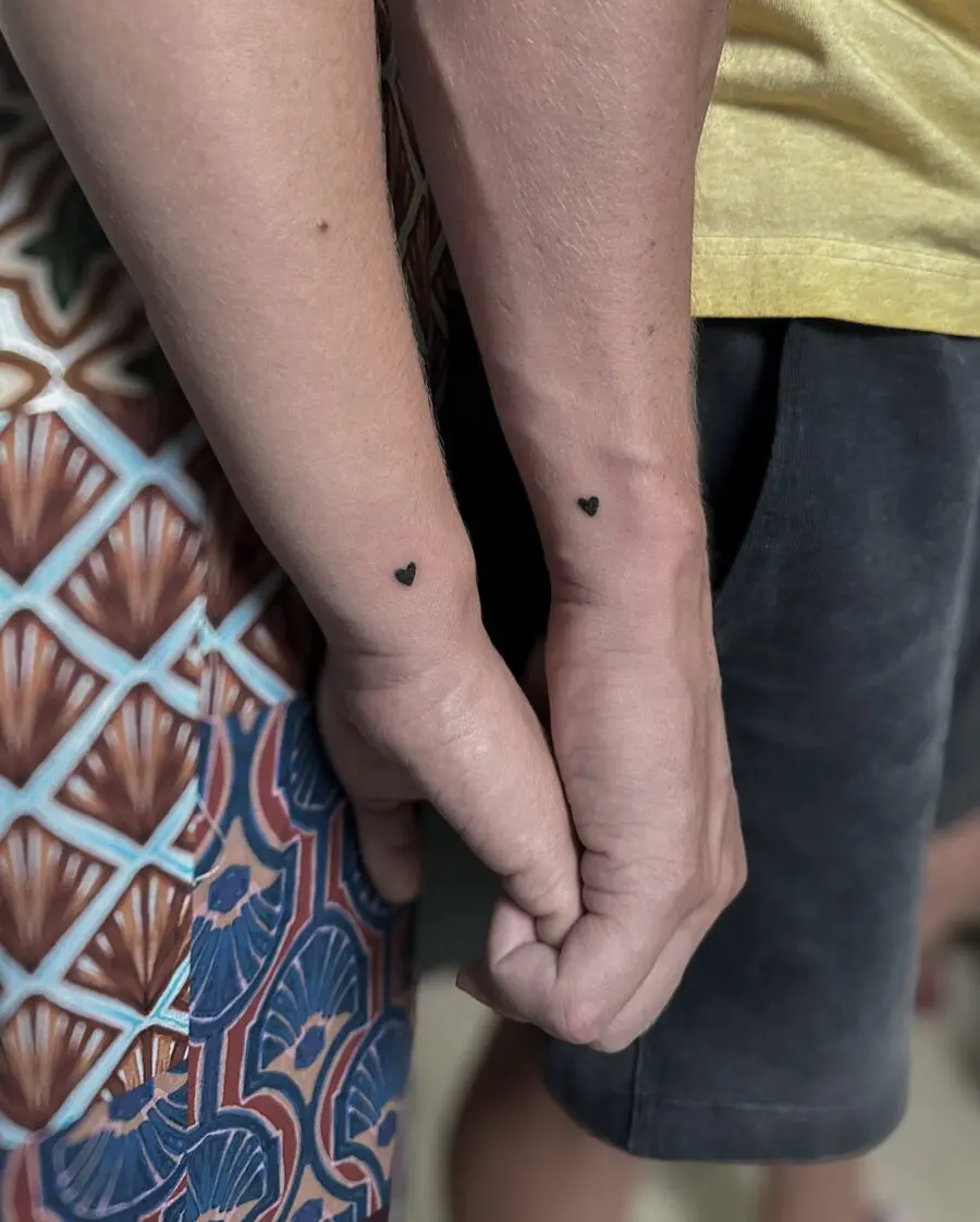 Minimalist heart tattoos on couple's wrists