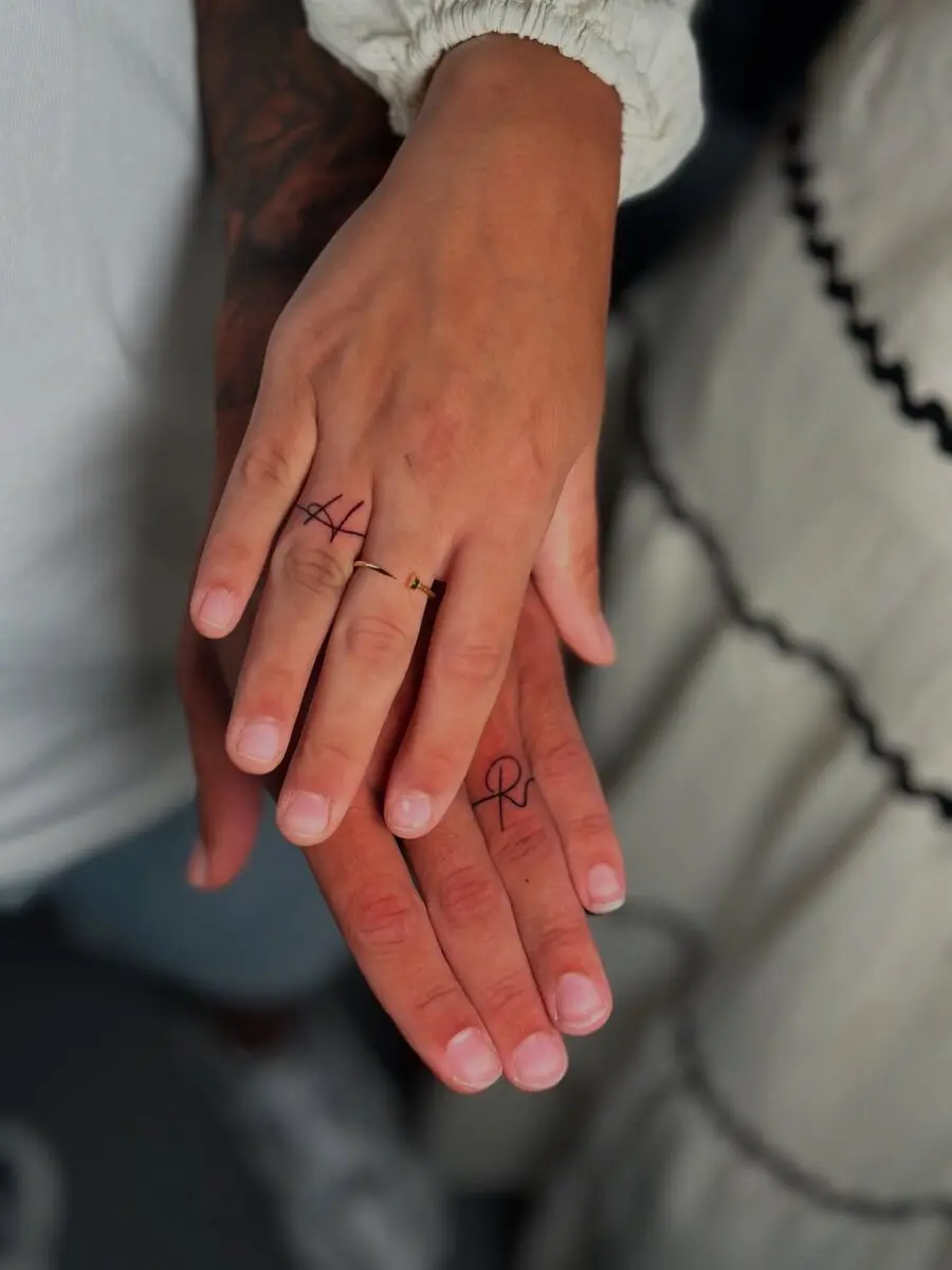 Minimalistic couple tattoos on intertwined hands