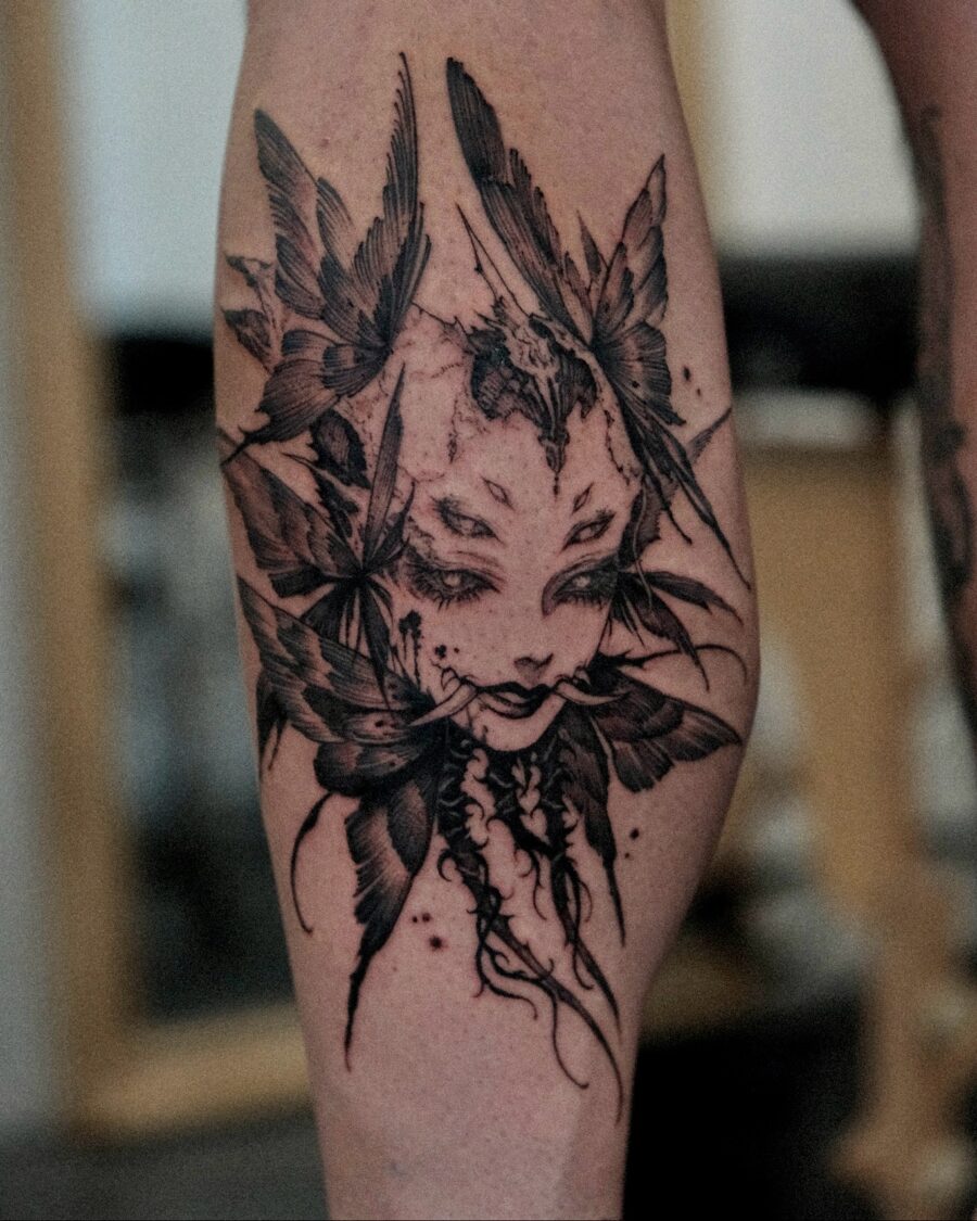 Intricate dark feminine tattoo with feathers