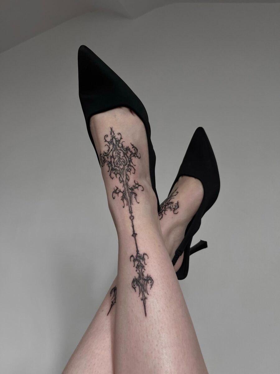 Elegant dark feminine tattoo on leg.