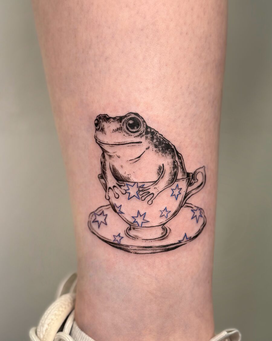 A playful frog nestled in a teacup