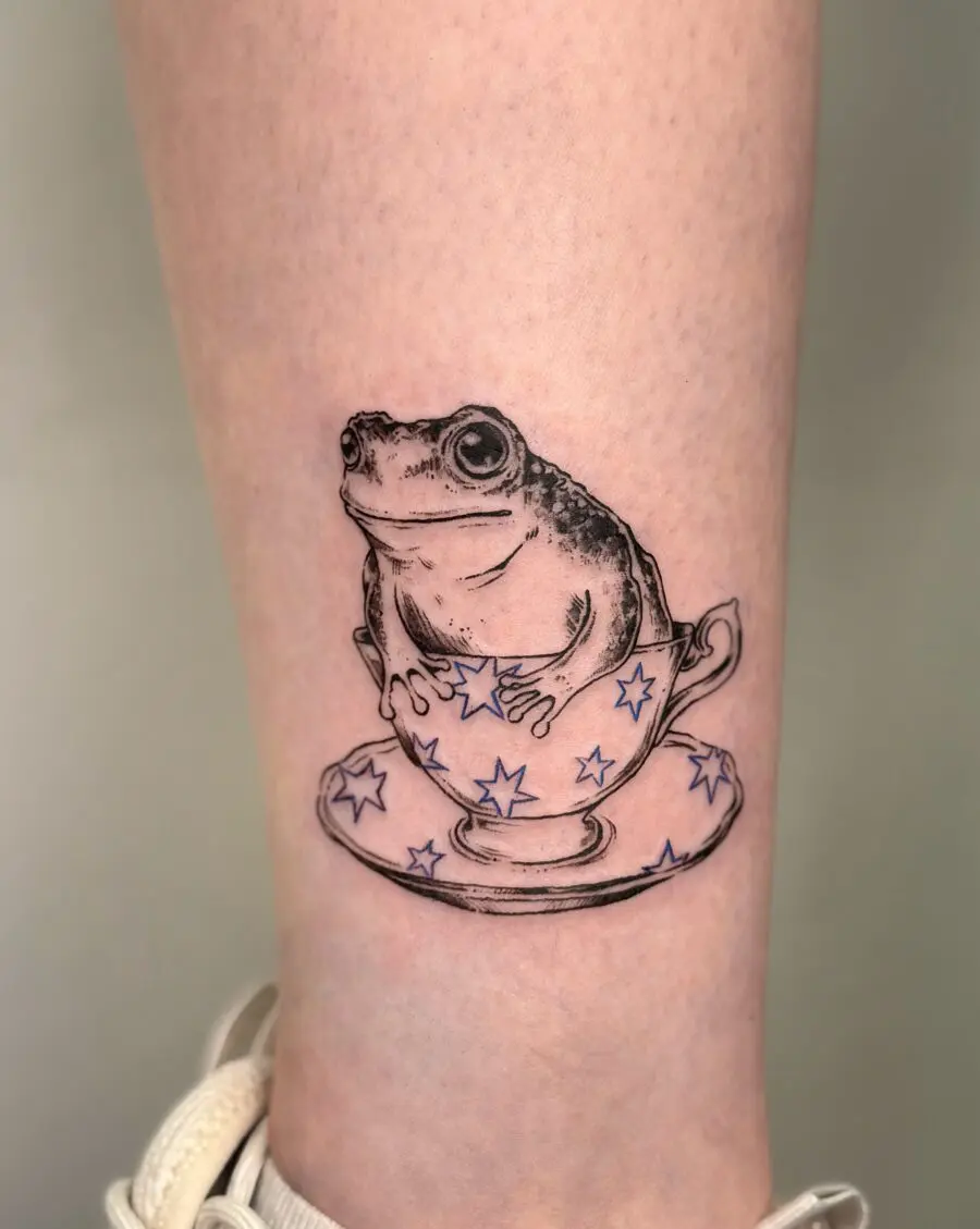 A playful frog nestled in a teacup