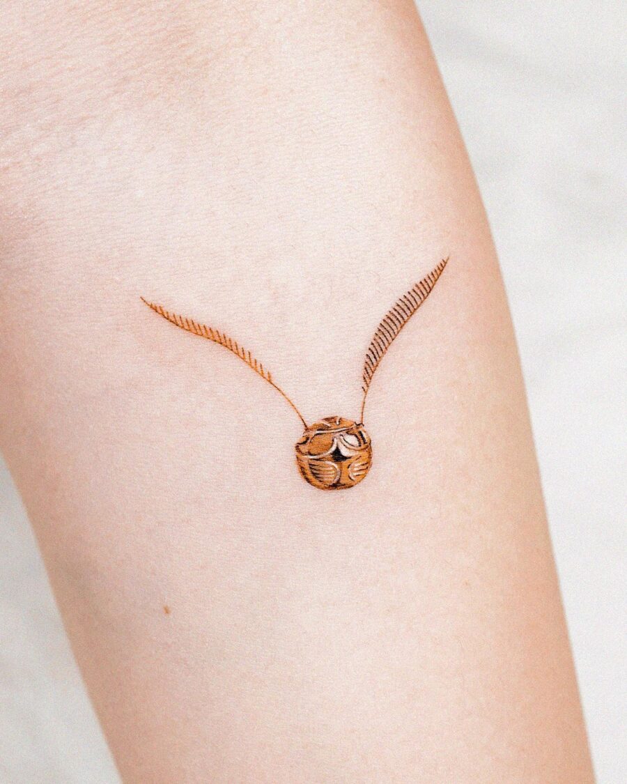 Elegant golden snitch tattoo design on skin