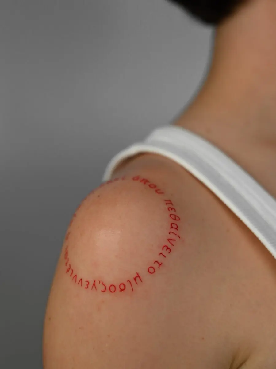 Unique Red Ink Text Tattoo on Shoulder