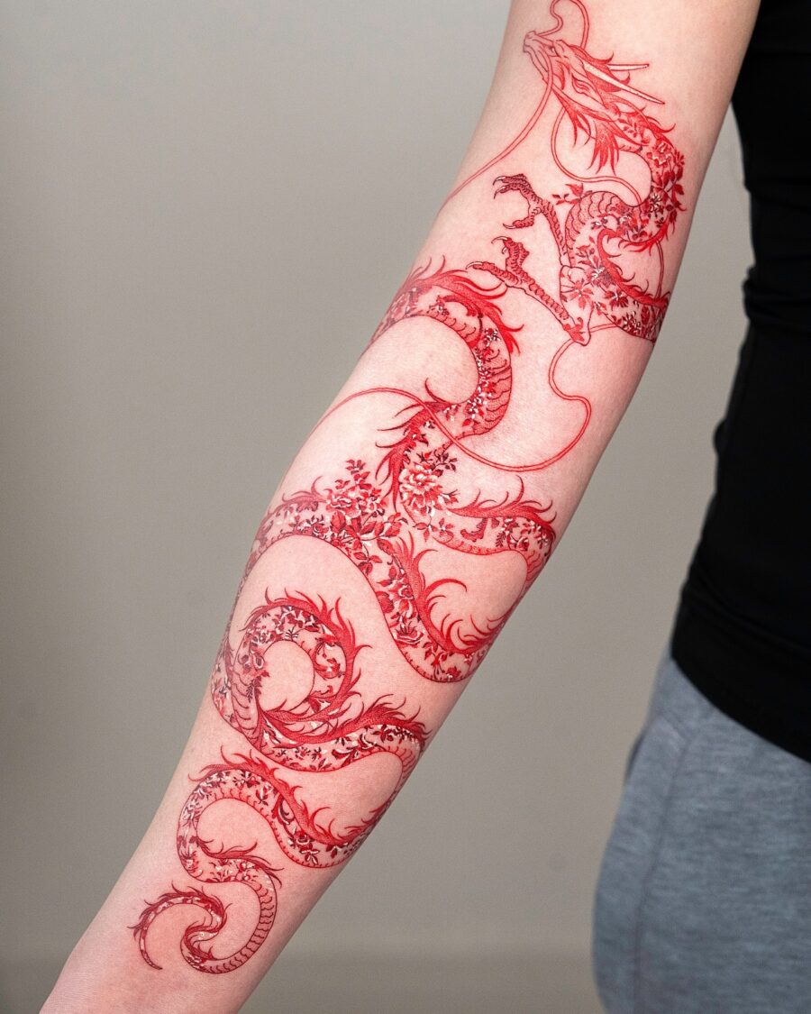 Intricate red ink dragon tattoo on forearm