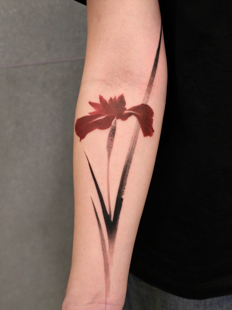 Striking red ink floral tattoo on the arm