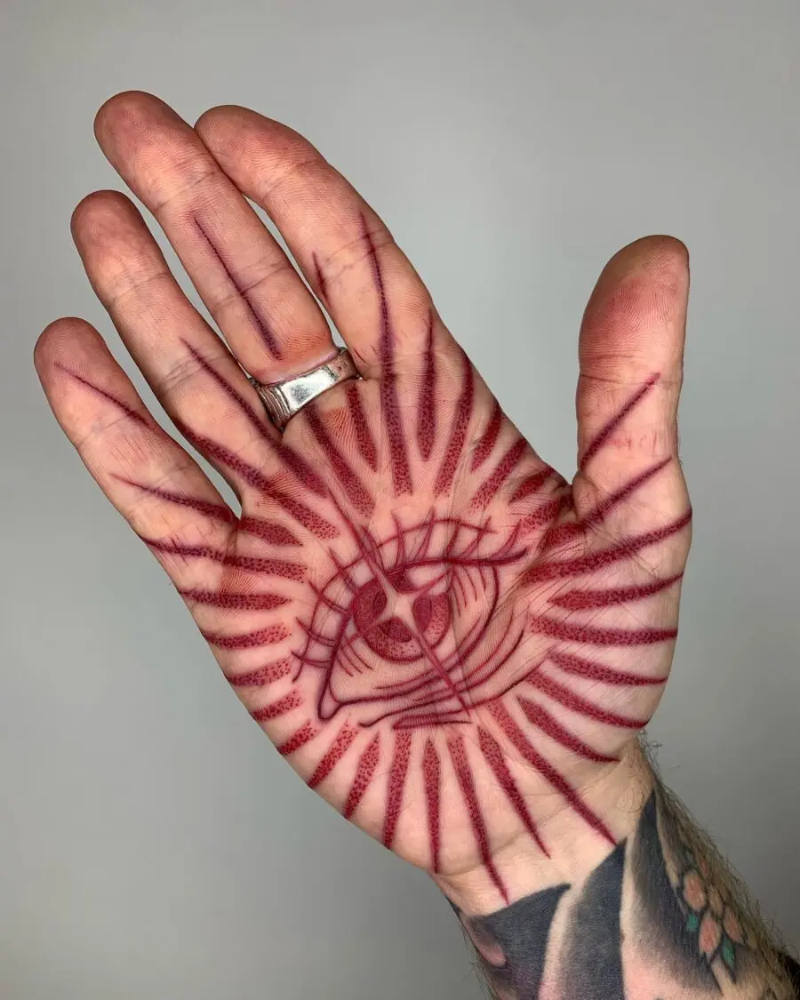 Intricate red ink eye tattoo design in hand
