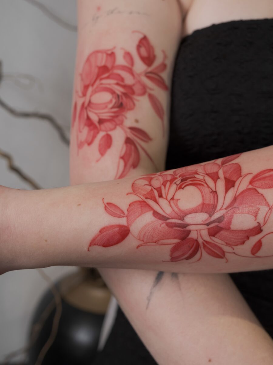 Elegant red ink peony tattoos on arms