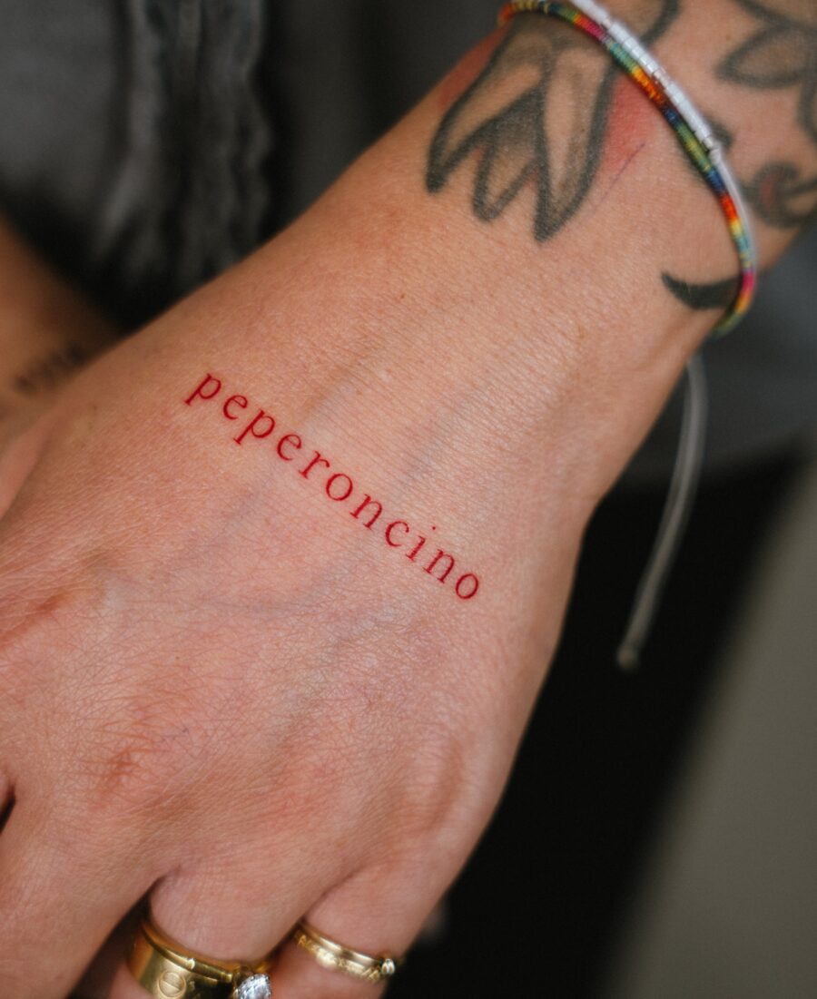 Bold red ink tattoo on hand showcases creativity
