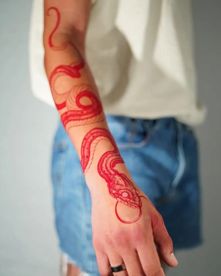 Intricate red ink snake tattoo on forearm