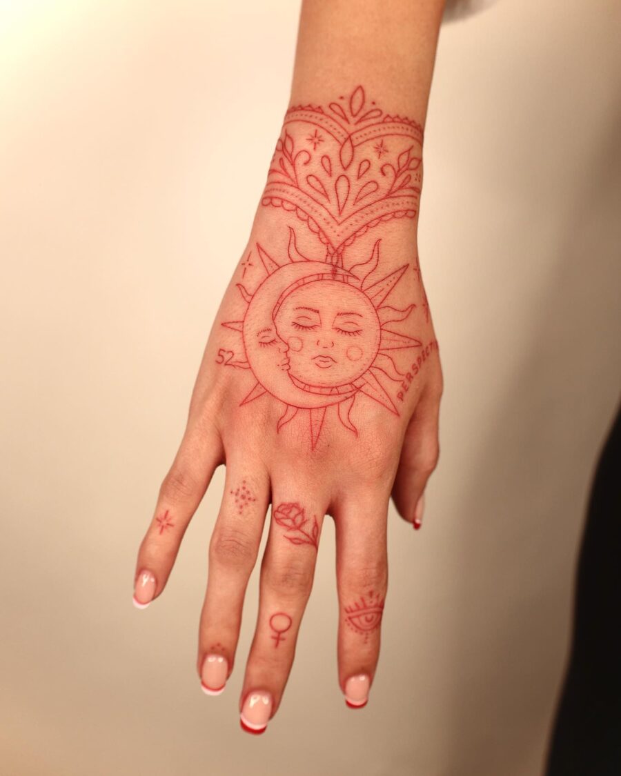 Vibrant red ink sun tattoo on hand