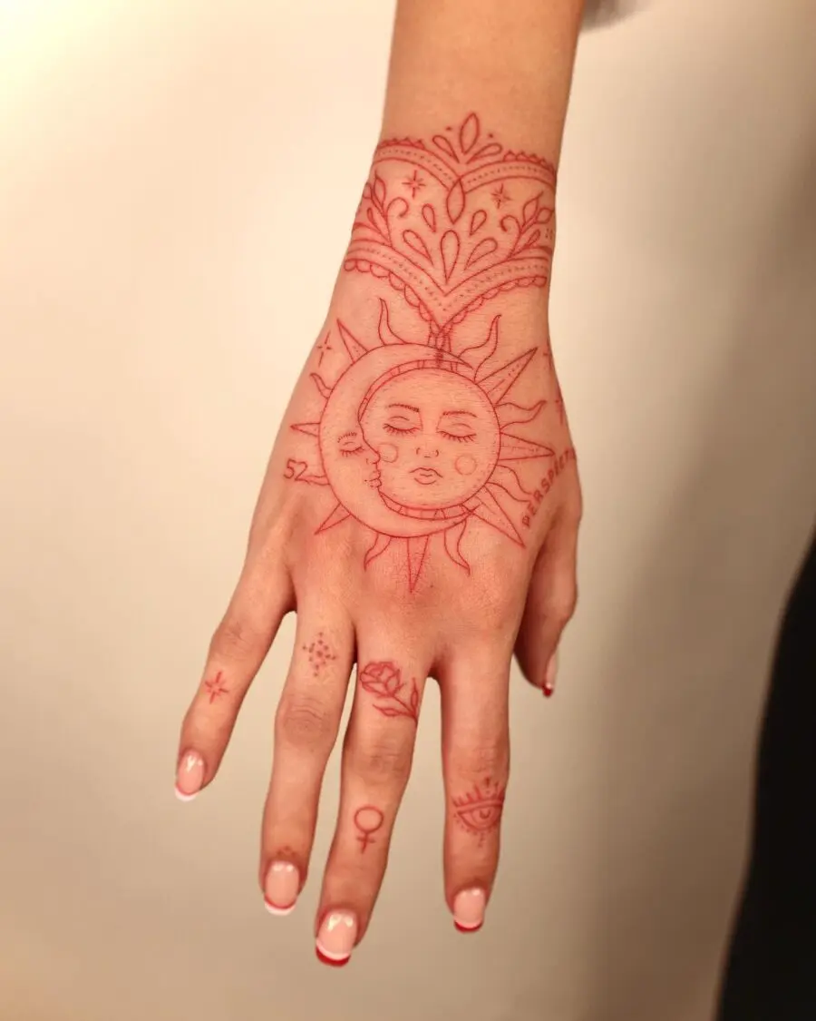 Vibrant red ink sun tattoo on hand