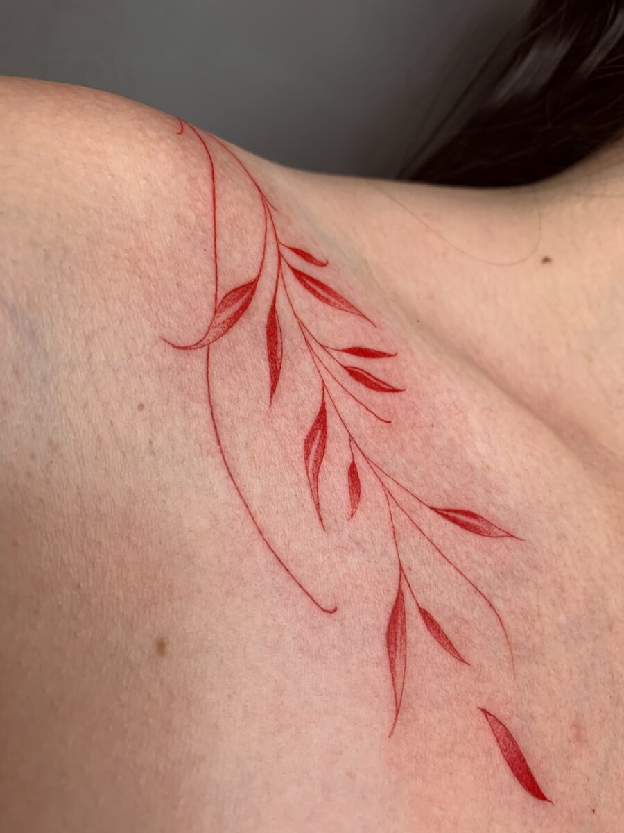 Delicate red ink leaf tattoo design on shoulder