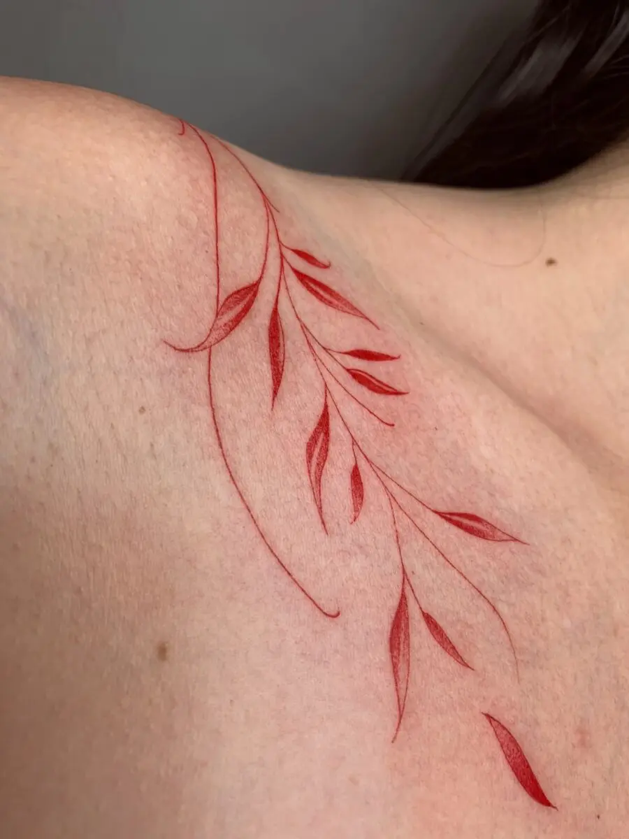 Delicate red ink leaf tattoo design on shoulder