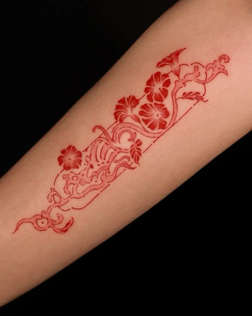 Intricate red ink floral arm tattoo design